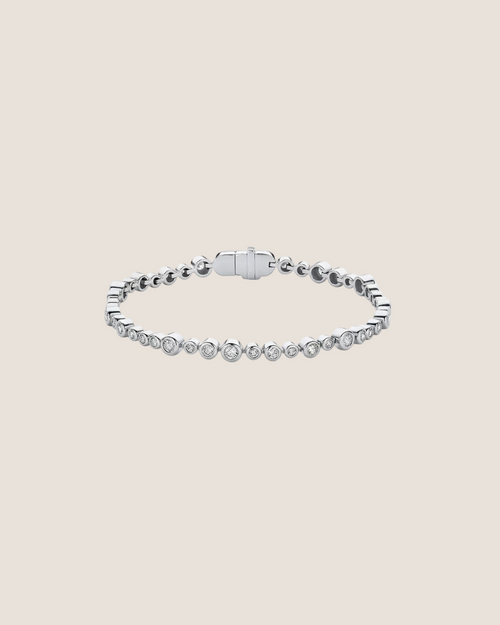 A silver tennis bracelet featuring a row of small round-cut clear stones along the front, with a polished clasp closure, shown on a plain white background.