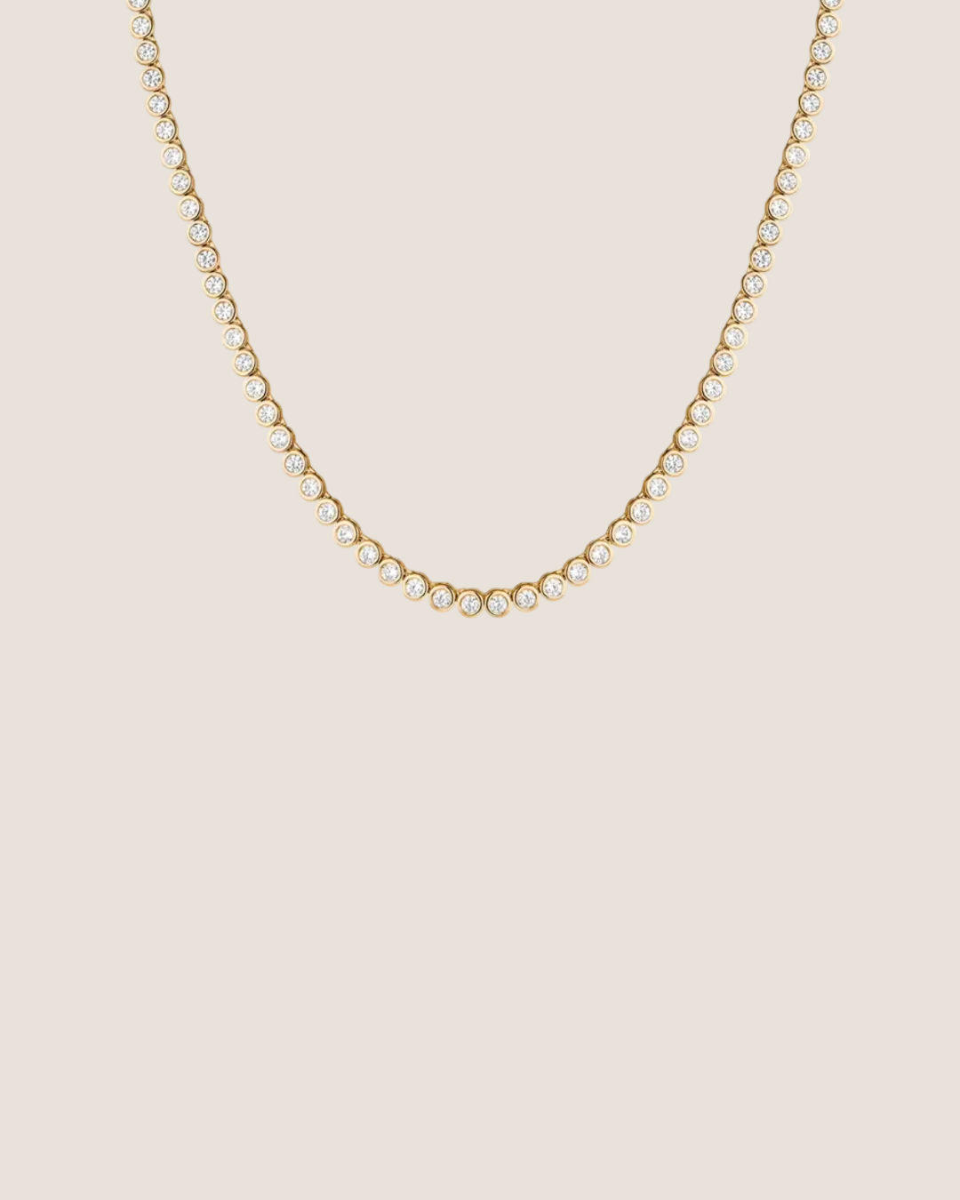 A delicate gold tennis necklace with small clear stones, photographed against a solid white background.