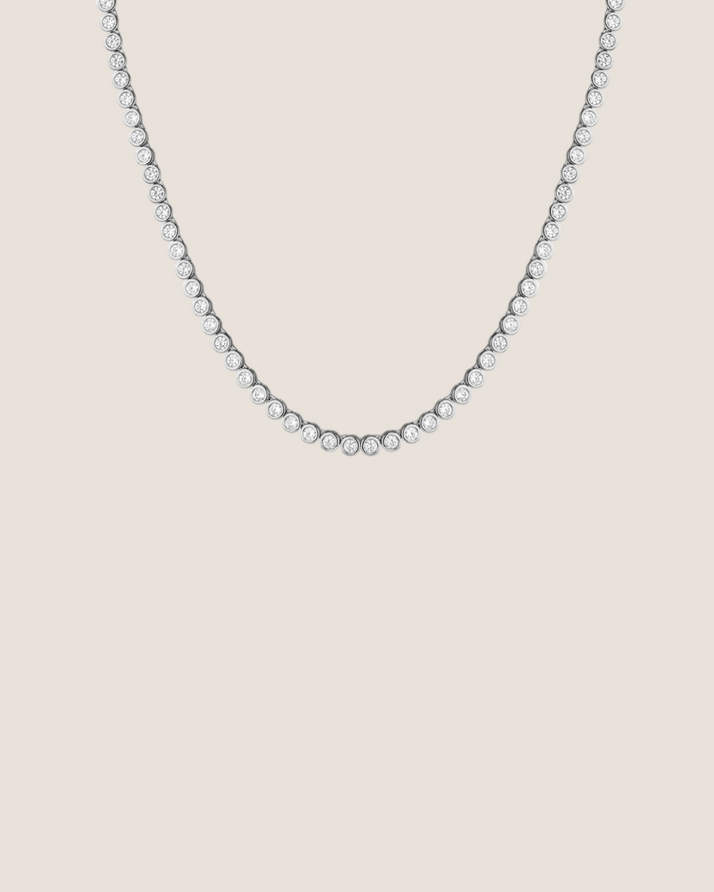 A delicate tennis-style necklace with small clear stones set in a silver-toned metal, shown against a plain white background.