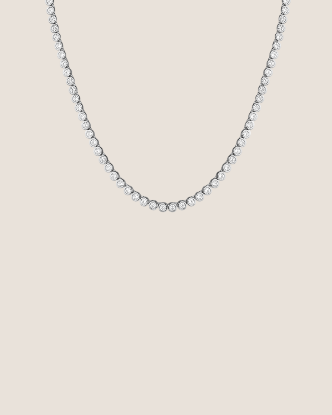 A delicate tennis-style necklace with small clear stones set in a silver-toned metal, shown against a plain white background.