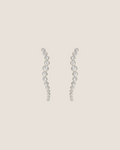 A pair of silver-toned dangle earrings with a wavy, cascading design set with clear round gemstones, shown against a plain white background.