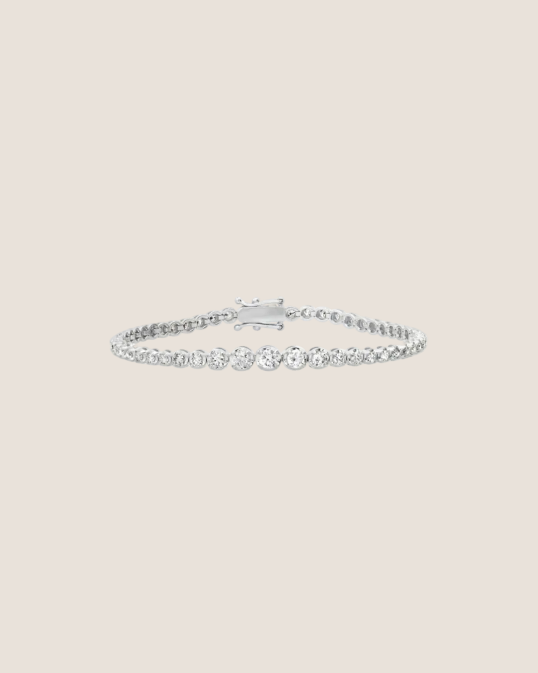 A delicate silver tennis bracelet with a row of clear round-cut stones, displayed on a clean white background with a soft reflection.