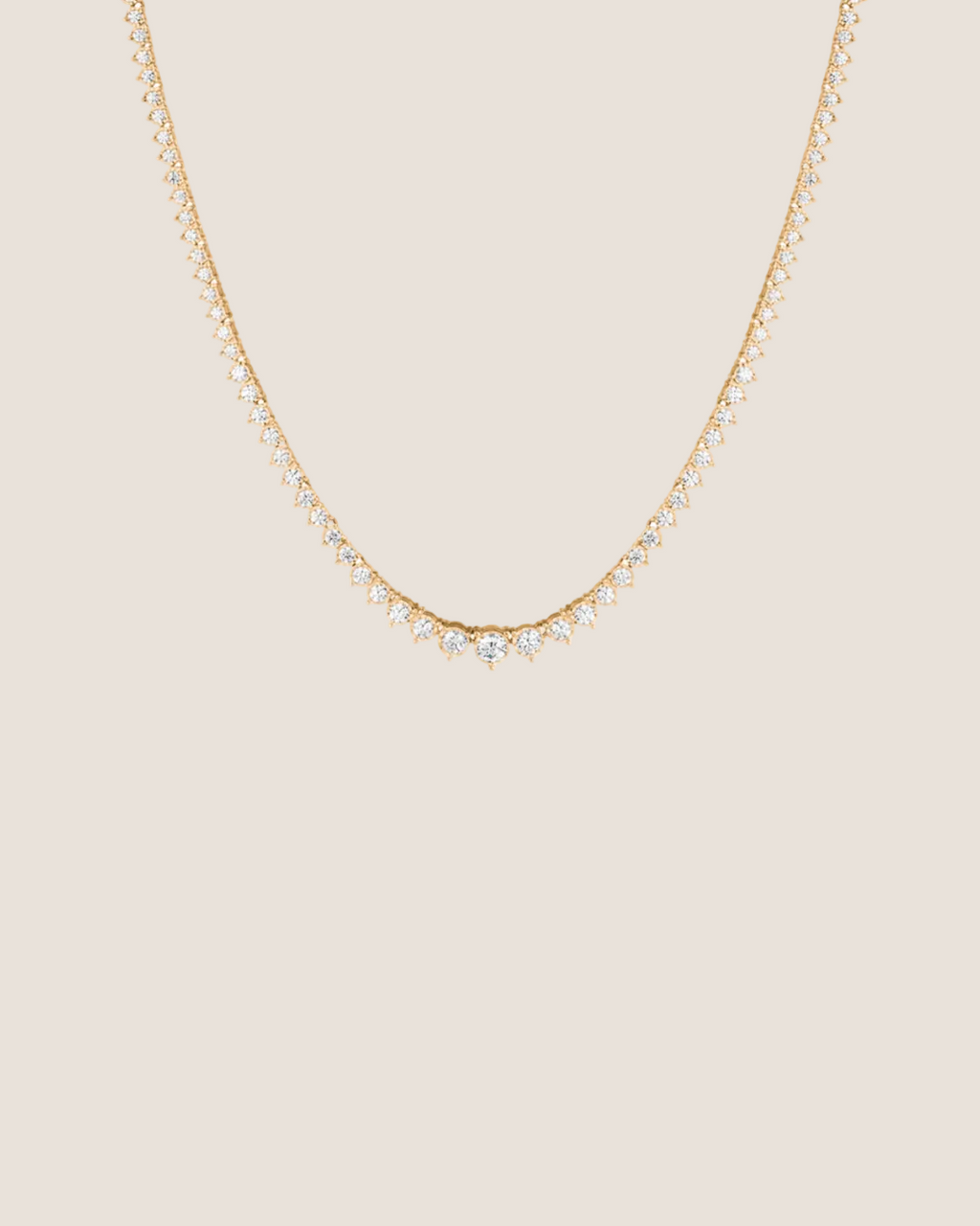 A delicate gold chain necklace featuring a V-shaped center adorned with small clear stones, set against a solid white background.