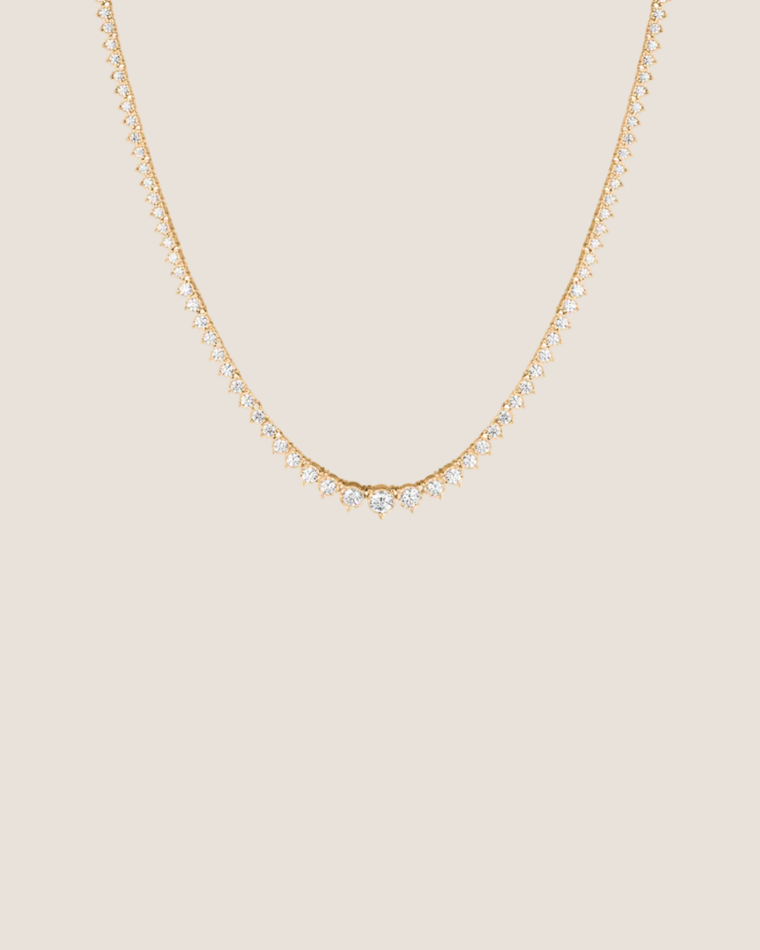 A delicate gold chain necklace featuring a V-shaped center adorned with small clear stones, set against a solid white background.