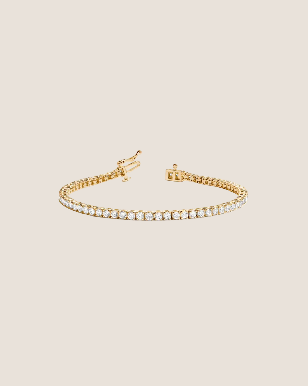 A gold tennis bracelet with a single row of clear round-cut gemstones, displayed on a clean white background.